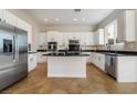 Bright kitchen featuring white cabinets, stainless steel appliances, a black countertop island, and tile flooring at 2365 Black River Falls Dr, Henderson, NV 89044