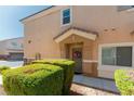 Exterior view of a townhouse entrance with a decorated front door and manicured bushes at 3609 Indigo Flower St # 1, North Las Vegas, NV 89084