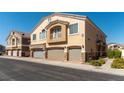 A tan two-story townhouse featuring a private balcony and individual one-car garages at 3609 Indigo Flower St # 1, North Las Vegas, NV 89084