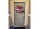 Close up of a gray front door adorned with patriotic wreath and dark doormat at 3609 Indigo Flower St # 1, North Las Vegas, NV 89084