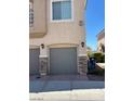 View of the garages attached to the condos with gray garage doors and stone veneer on the side columns at 3609 Indigo Flower St # 1, North Las Vegas, NV 89084