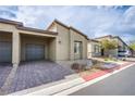 Contemporary home with desert landscaping, brick driveway, and a two-car garage at 7517 Crested Moon St, North Las Vegas, NV 89084