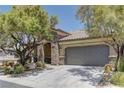 Attractive single-story home with a two-car garage, stone accents, and lush trees at 9120 Parkstone Ave, Las Vegas, NV 89178