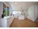 Spacious kitchen with white cabinets, island, wood floors, and contemporary lighting fixtures at 1371 Cumulus Ct, Henderson, NV 89014