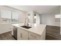 Bright kitchen featuring an island with stainless steel sink and faucet, light countertops, and a view to the living area at 175 Strada Fontana, Henderson, NV 89011