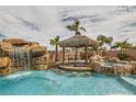 Beautiful pool area with tiki bar, waterfall, mature palm trees and adjacent spa at 3892 Pasilla Ave, Las Vegas, NV 89118