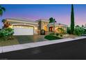 Beautiful single-story home featuring well-manicured landscaping, a spacious garage, and a brick driveway at dusk at 4286 Pacifico Ln, Las Vegas, NV 89135
