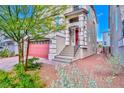 Stylish home with a red front door and garage, complemented by tidy landscaping, side stairs, and a charming aesthetic at 7032 Steele Canyon St, Las Vegas, NV 89118