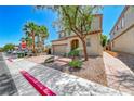 Two-story home with neutral color palette, desert landscaping, and brick paved path to the front door at 708 Point Bluff St, Henderson, NV 89002