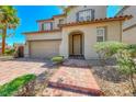 Charming two-story home with red brick driveway and walkway with manicured landscaping and tan stucco at 708 Point Bluff St, Henderson, NV 89002