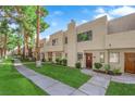 Townhouse exterior featuring a sidewalk, manicured lawn, desert landscaping and mature trees at 2661 Ruthe Duarte Ave, Las Vegas, NV 89121