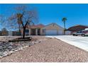 Single-story home featuring desert landscaping, a two-car garage, and long driveway at 475 E Robindale Rd, Las Vegas, NV 89123