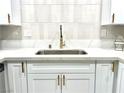 Close-up of a kitchen sink with quartz countertops and white cabinets with gold hardware at 5191 Caliente St # 84, Las Vegas, NV 89119