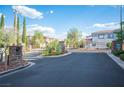 Gated community entrance with stone pillars, lush landscaping, and well-maintained asphalt at 6029 Allanche Ave, Las Vegas, NV 89141