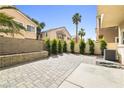 Private backyard with a paved patio, bordered by manicured shrubs and trees at 6050 Golden Corral Trl # 102, Henderson, NV 89011