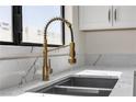 Close-up of a stylish kitchen sink with a modern gold faucet and white marble countertops by a window at 6204 Robin Hood Cir, Las Vegas, NV 89108