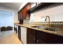 Kitchen featuring granite counters, tile backsplash, dark cabinets, modern appliances, and washer/dryer at 634 Oakmont Ave # 1903, Las Vegas, NV 89109