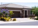Inviting single-story home showcasing a two-car garage, desert landscaping, and pops of color from blooming plants at 10262 Havasu Falls St, Las Vegas, NV 89141