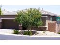 Well-maintained single-story house with a two-car garage, stone accents, and a young tree in the front yard at 10262 Havasu Falls St, Las Vegas, NV 89141