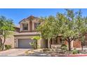 Charming two-story home with a gray garage door and desert landscaping and manicured green foliage at 11625 Cabo Del Verde Ave, Las Vegas, NV 89138