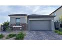 Two-car garage featuring a gray door, stone accents, and a paved driveway at 12565 Huckleberry Oak Ave, Las Vegas, NV 89138