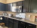 This kitchen boasts granite countertops, gas range, dark wood cabinets, and stainless steel microwave at 152 Lotus Vale Ave, Las Vegas, NV 89123
