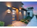 Stylish front entrance featuring a blue door, modern lighting fixtures, and a brick pathway surrounded by lush landscaping at 2578 Skylark Trail St, Henderson, NV 89044
