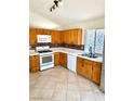 Functional kitchen with light wood cabinets, white appliances, and a tiled backsplash, complemented by ceramic tile flooring at 3665 Lucky Horseshoe Ct, Las Vegas, NV 89129