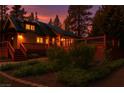 Two-story home featuring a large wooden deck, lush landscaping, and warm exterior lighting at 4178 Matterhorn Way, Las Vegas, NV 89124