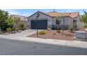 Charming single-story home with a desert landscaped front yard, a dark gray garage door, and a red tiled roof at 509 Regal Robin Way, North Las Vegas, NV 89084
