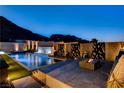 Stunning pool area with water features, modern decor, and mountain views at twilight at 10228 Shell Star Ave, Las Vegas, NV 89135