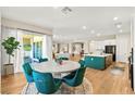Bright dining area with modern teal chairs around a circular table, and access to outdoor area via glass doors at 10906 Mila Landing Ave, Las Vegas, NV 89166