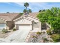 Inviting single-story home with a tile roof, two-car garage, desert landscaping, and palm tree at 1978 Kachina Mountain Dr, Henderson, NV 89012