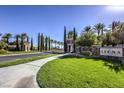 Scenic community entrance with lush greenery, stone signage, and elegant guard houses under a clear blue sky at 5162 Estasi St, Las Vegas, NV 89135