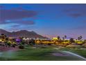 Scenic view of a lush golf course with sprinklers running, set against a mountain backdrop at dusk at 5162 Estasi St, Las Vegas, NV 89135