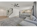Bright living room with a ceiling fan, open staircase, and a large gray sectional sofa at 5250 Chester Creek Ct, Las Vegas, NV 89141