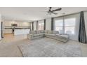 Open-concept living space with a gray sofa, large windows, and an adjacent kitchen with granite counters at 5250 Chester Creek Ct, Las Vegas, NV 89141