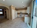 Neutral kitchen with white appliances and cabinets, recessed lighting and tiled floors next to staircase at 5861 Varese Dr, Las Vegas, NV 89141