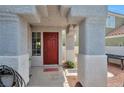 Covered front porch with red door and desert-style landscaping offers a warm welcome at 9348 Buckhaven Dr, Las Vegas, NV 89117