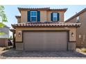 Charming home with a tiled roof, tan stucco exterior, and a convenient two-car garage with brick driveway at 9690 Langden Brook St, Las Vegas, NV 89178