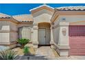 Close up of front entrance with desert landscaping, a tiled walkway, and a view of the two car garage at 983 Cutter St, Henderson, NV 89011