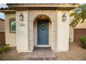 Close-up of a front door adorned with a wreath, flanked by sconces and a stone-paved path at 11044 Camden Bay St, Las Vegas, NV 89179