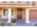 Charming home entrance with decorative columns, a barrel planter, and an ornate wrought iron front door at 6403 Brandon Hills Ct, Las Vegas, NV 89139