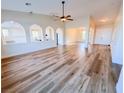 Open-concept living room with new flooring, fan and arched entryways to dining and kitchen at 8616 Willow Cabin St, Las Vegas, NV 89131