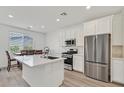 Modern kitchen featuring stainless steel appliances, a quartz island, and an adjacent dining area with a view at 8852 Flora Run Ave, Las Vegas, NV 89166