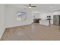 Open-concept living room with hardwood floors leading to a well-lit kitchen and dining area with stainless steel appliances at 8852 Flora Run Ave, Las Vegas, NV 89166