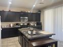 Well-lit kitchen boasts modern black cabinets, a practical island, and granite countertops at 933 Kimbark Ave, Las Vegas, NV 89148