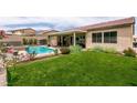 Lush backyard featuring a well-maintained lawn, covered patio, and a sparkling swimming pool for relaxation at 1413 Gentle Brook St, North Las Vegas, NV 89084