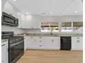 Modern kitchen featuring white cabinets, sleek black appliances, and granite countertops at 2402 El Cid Ct, Henderson, NV 89014