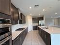 Elegant kitchen featuring stainless steel appliances, dark cabinetry, an island, and bright countertops at 2620 Tolmezzo St, Henderson, NV 89044